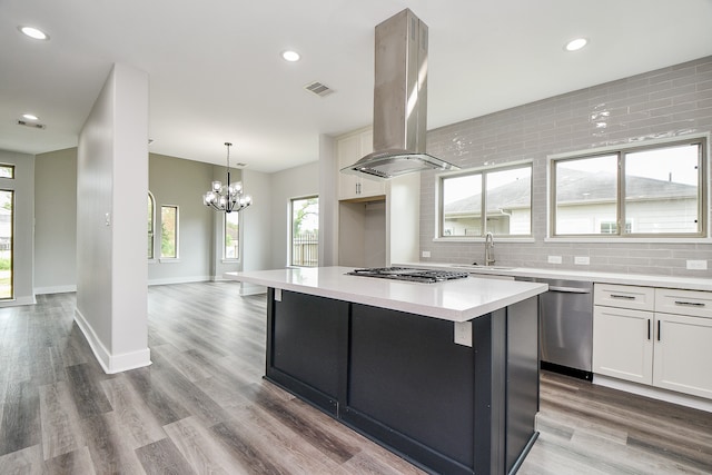 kitchen with decorative backsplash, island range hood, white cabinetry, and light hardwood / wood-style flooring