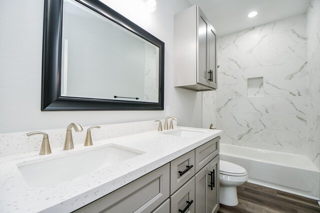 full bathroom with vanity, toilet, tiled shower / bath combo, and hardwood / wood-style floors