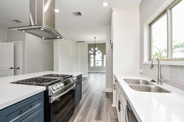 kitchen with island range hood, plenty of natural light, stainless steel gas stove, and sink