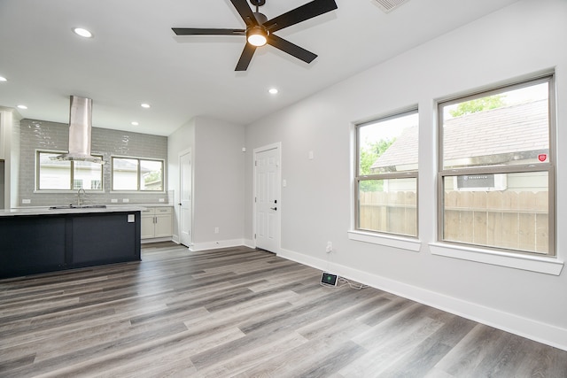 unfurnished living room featuring a wealth of natural light, hardwood / wood-style floors, sink, and ceiling fan