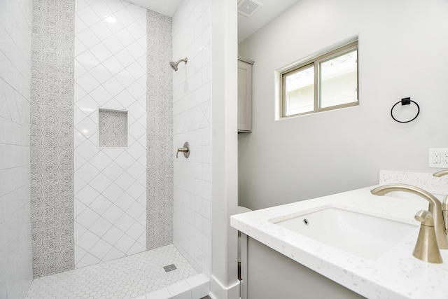 bathroom featuring tiled shower and vanity