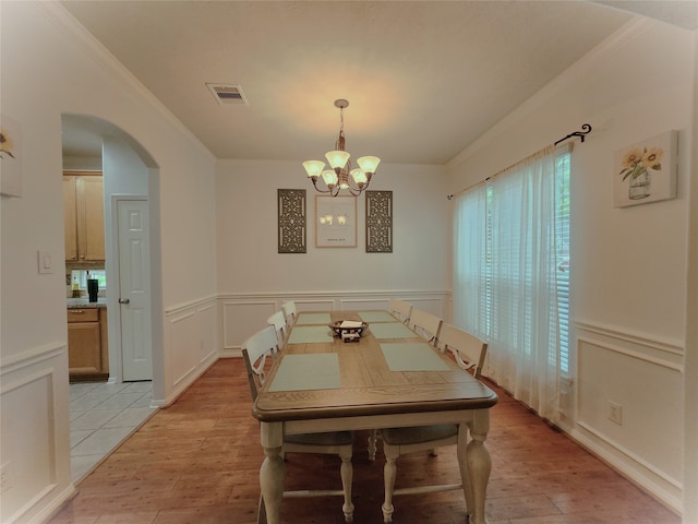 dining area with ornamental molding, a chandelier, and light hardwood / wood-style floors