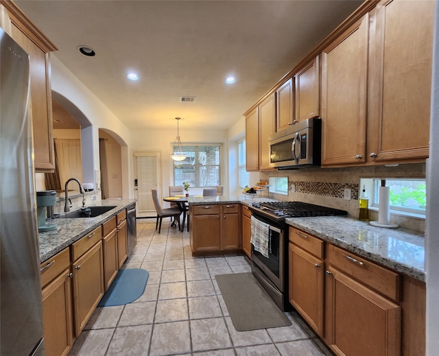 kitchen with appliances with stainless steel finishes, a wealth of natural light, kitchen peninsula, and sink