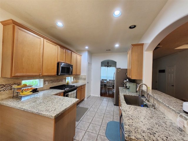 kitchen with a wealth of natural light, sink, light stone countertops, and appliances with stainless steel finishes