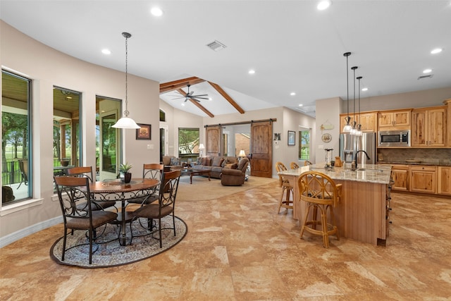 dining space with a barn door, ceiling fan, sink, and vaulted ceiling with beams