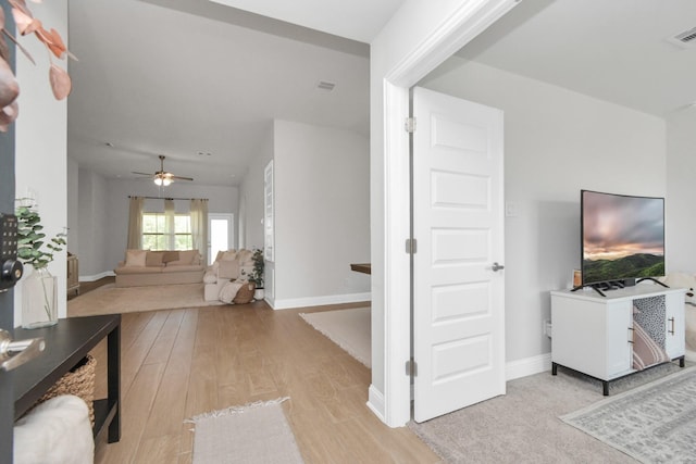 living room featuring ceiling fan, wood finished floors, visible vents, and baseboards