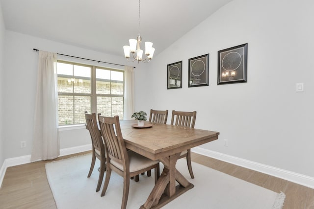 dining room with light hardwood / wood-style floors, an inviting chandelier, and vaulted ceiling