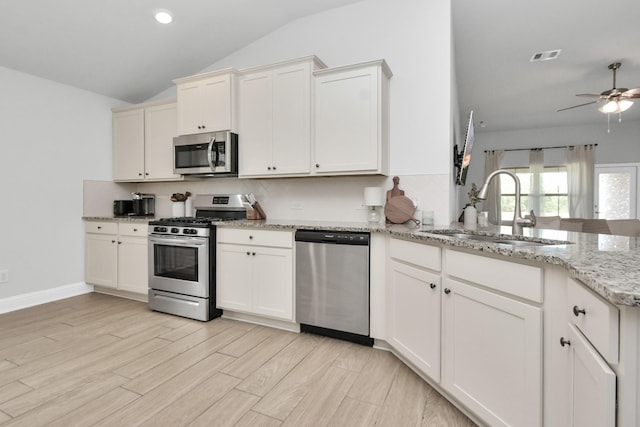 kitchen with light stone countertops, stainless steel appliances, white cabinetry, and sink