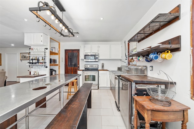 kitchen featuring wooden counters, white cabinets, and stainless steel appliances