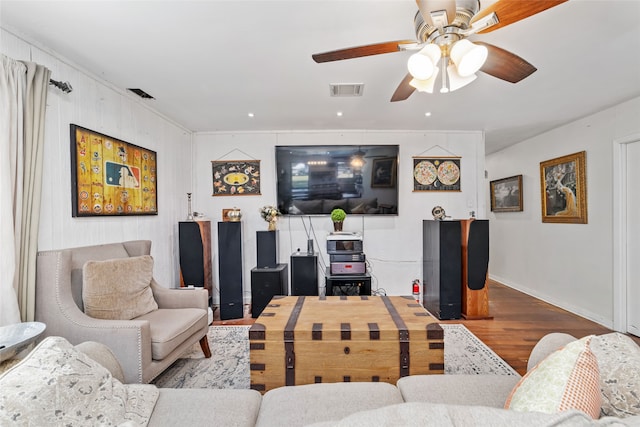 living room with ceiling fan, hardwood / wood-style floors, and wooden walls