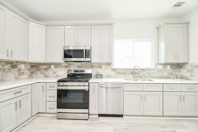 kitchen with light wood-type flooring, stainless steel appliances, tasteful backsplash, and sink