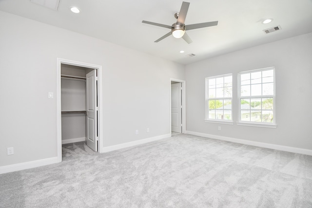 unfurnished bedroom with light colored carpet, ceiling fan, a spacious closet, and a closet