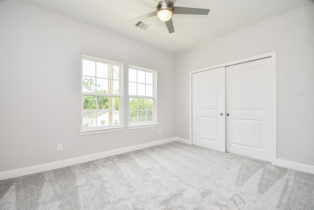 unfurnished bedroom featuring light colored carpet, ceiling fan, and a closet