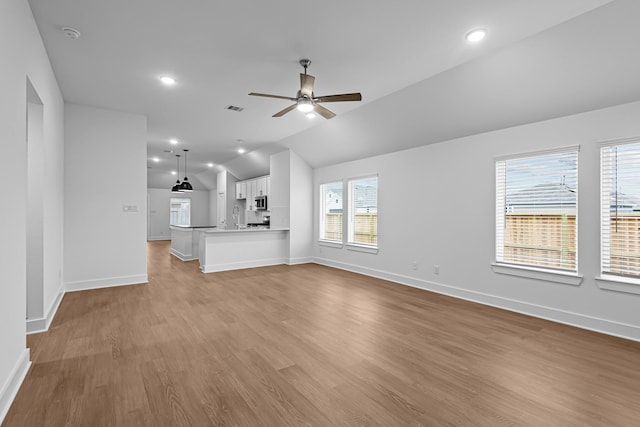 unfurnished living room featuring lofted ceiling, sink, light hardwood / wood-style floors, and ceiling fan