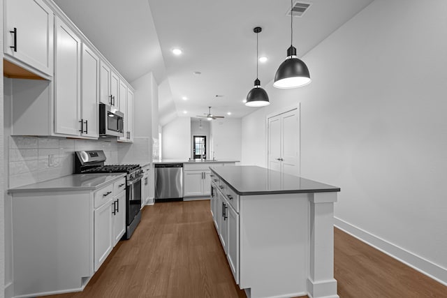 kitchen with pendant lighting, stainless steel appliances, kitchen peninsula, and white cabinets