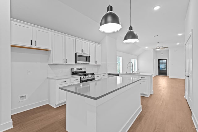 kitchen featuring white cabinetry, lofted ceiling, hanging light fixtures, kitchen peninsula, and stainless steel appliances