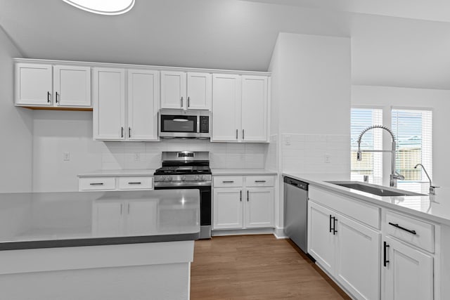 kitchen with white cabinetry, appliances with stainless steel finishes, light hardwood / wood-style floors, and sink