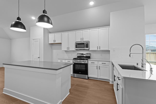 kitchen with white cabinetry, stainless steel appliances, sink, and hanging light fixtures