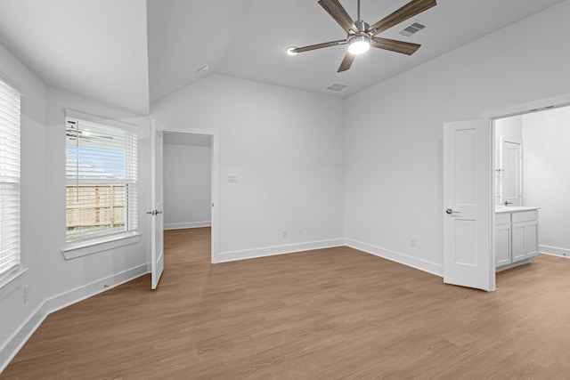 unfurnished bedroom featuring lofted ceiling, ensuite bath, ceiling fan, and light hardwood / wood-style flooring