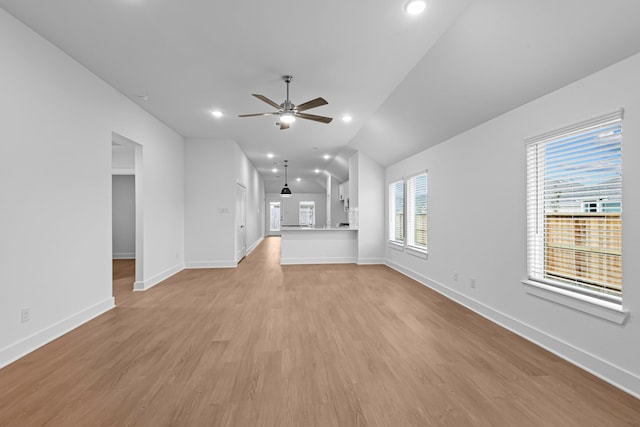 unfurnished living room with ceiling fan, vaulted ceiling, and light wood-type flooring