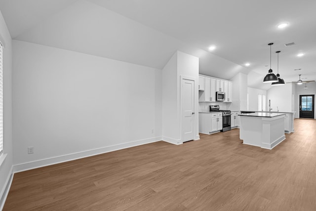 kitchen with lofted ceiling, white cabinetry, hanging light fixtures, stainless steel appliances, and a kitchen island