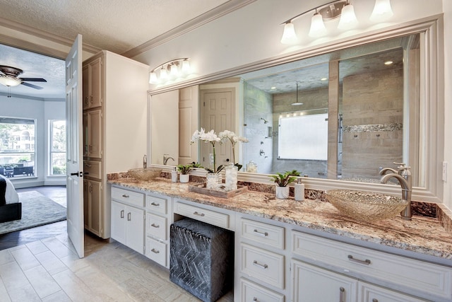 bathroom with crown molding, vanity, tiled shower, ceiling fan, and a textured ceiling