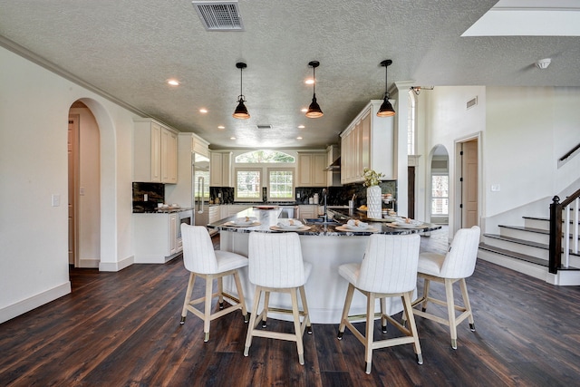 kitchen featuring pendant lighting, a breakfast bar, decorative backsplash, and dark hardwood / wood-style flooring