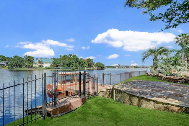 view of dock featuring a water view, a lawn, and a patio