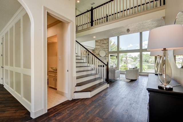 entryway featuring ornamental molding, dark wood-type flooring, and a towering ceiling