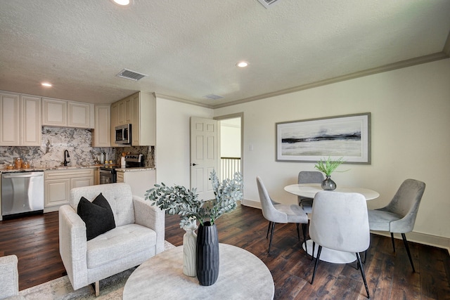 living room featuring dark wood-type flooring, a textured ceiling, crown molding, and sink