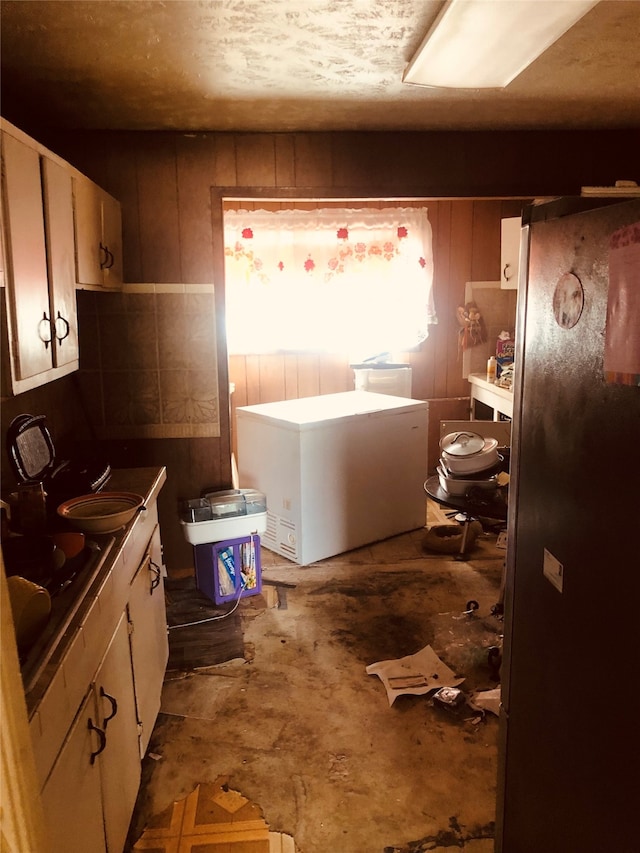 kitchen with stainless steel refrigerator and wooden walls