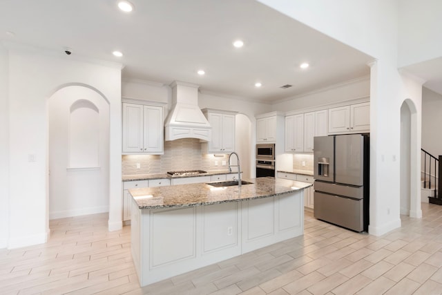 kitchen with premium range hood, stainless steel appliances, white cabinetry, and sink