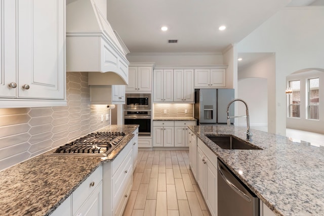 kitchen featuring white cabinets, appliances with stainless steel finishes, crown molding, and sink