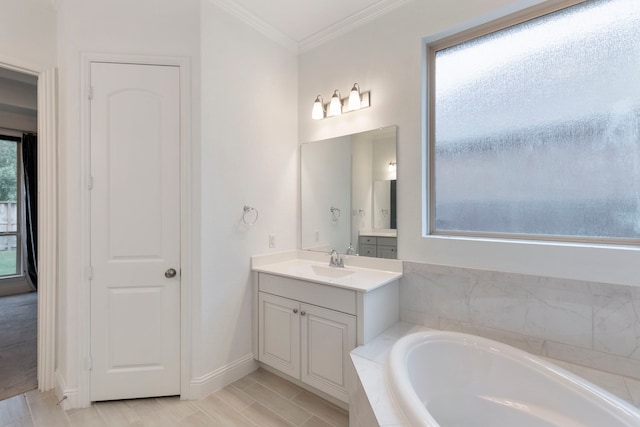 bathroom featuring ornamental molding, vanity, a healthy amount of sunlight, and a bathtub