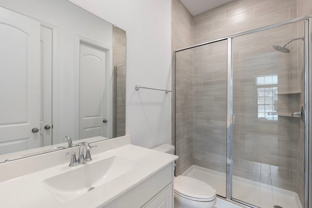 bathroom featuring vanity, toilet, and a shower with door