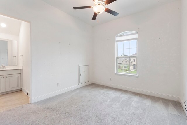 unfurnished bedroom with light carpet, connected bathroom, sink, and ceiling fan