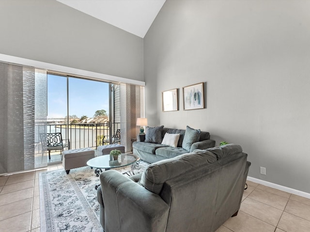 tiled living room featuring high vaulted ceiling and a water view