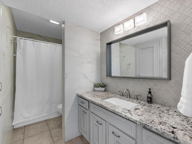 bathroom with vanity, toilet, curtained shower, tile walls, and tile patterned floors