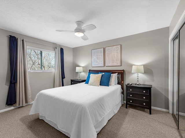 carpeted bedroom with a textured ceiling, ceiling fan, and a closet