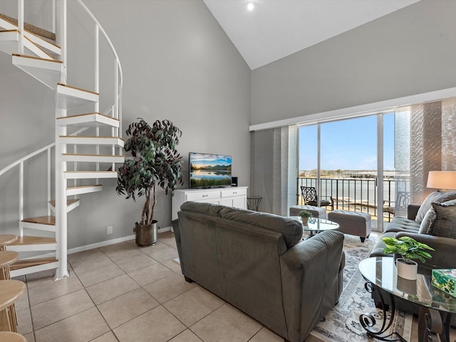 living area featuring light tile patterned floors, baseboards, high vaulted ceiling, and stairway