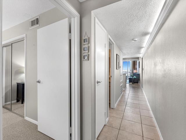 corridor with a textured ceiling and light tile patterned floors