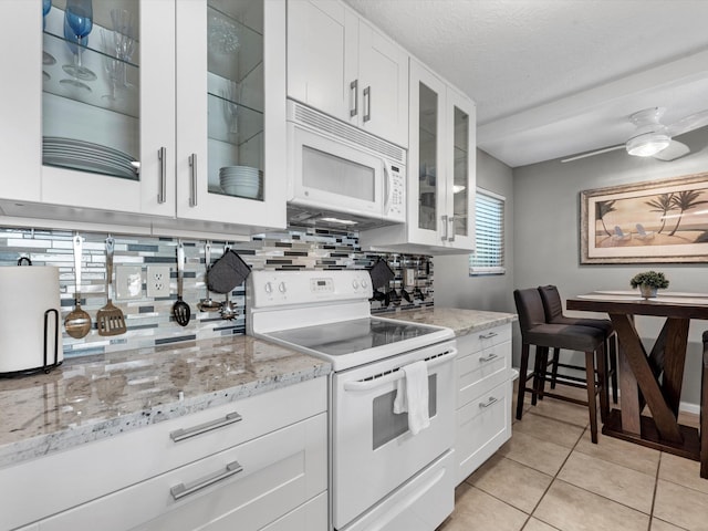 kitchen with white appliances, tasteful backsplash, ceiling fan, light stone counters, and white cabinets