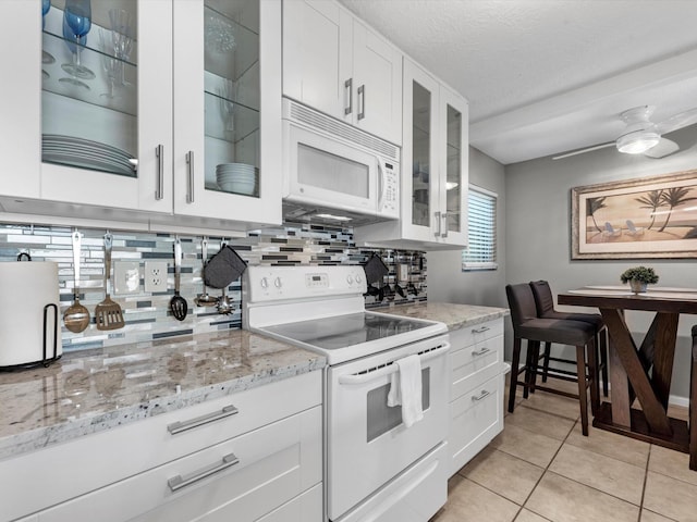 kitchen featuring tasteful backsplash, white appliances, white cabinetry, and light tile patterned floors