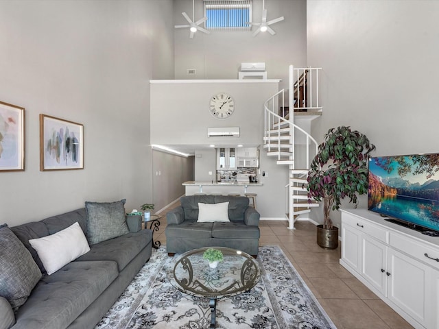 living room featuring light tile patterned floors, a ceiling fan, stairway, a high ceiling, and baseboards