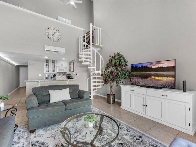 living area with baseboards, an AC wall unit, a towering ceiling, stairs, and light tile patterned flooring