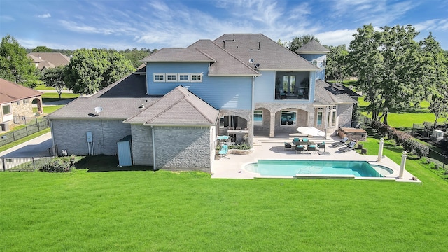 rear view of property featuring a fenced in pool, a lawn, and a patio