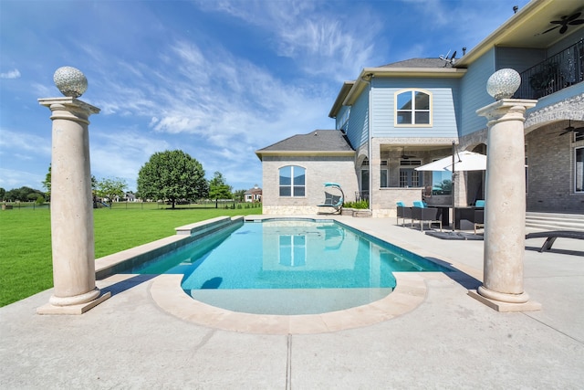 view of swimming pool featuring ceiling fan, a lawn, and a patio area