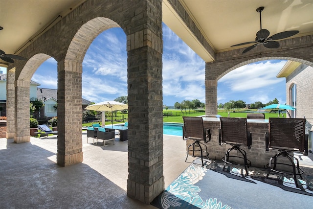 view of patio with ceiling fan, an outdoor hangout area, and a bar