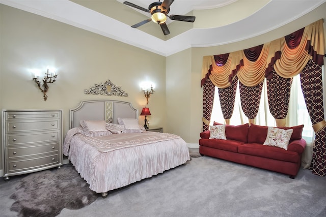 carpeted bedroom with a tray ceiling, ornamental molding, and ceiling fan