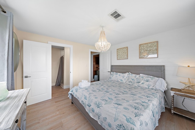 bedroom featuring a closet, a chandelier, wooden walls, and light hardwood / wood-style floors